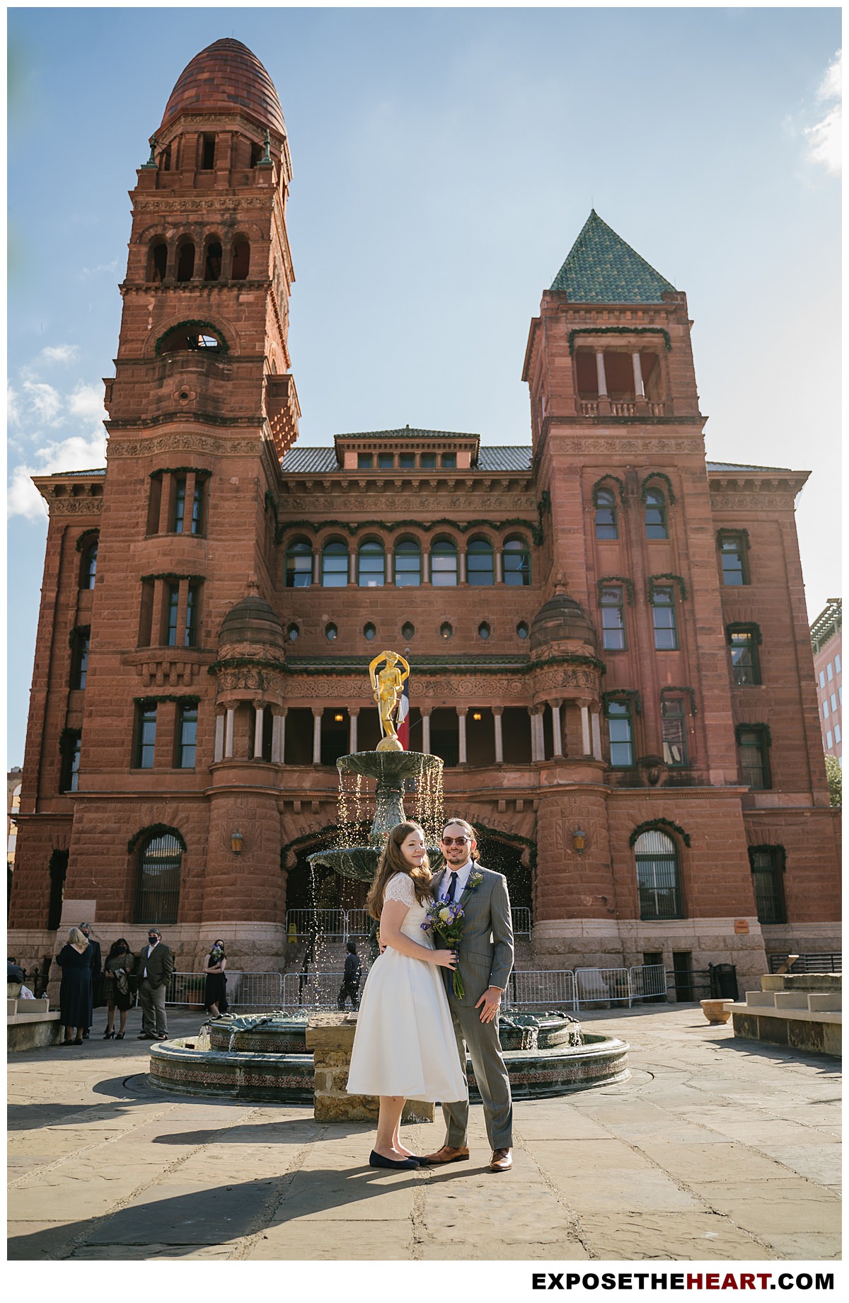 Bride and Groom posing in front of Bexar county courthouse fountain after getting married