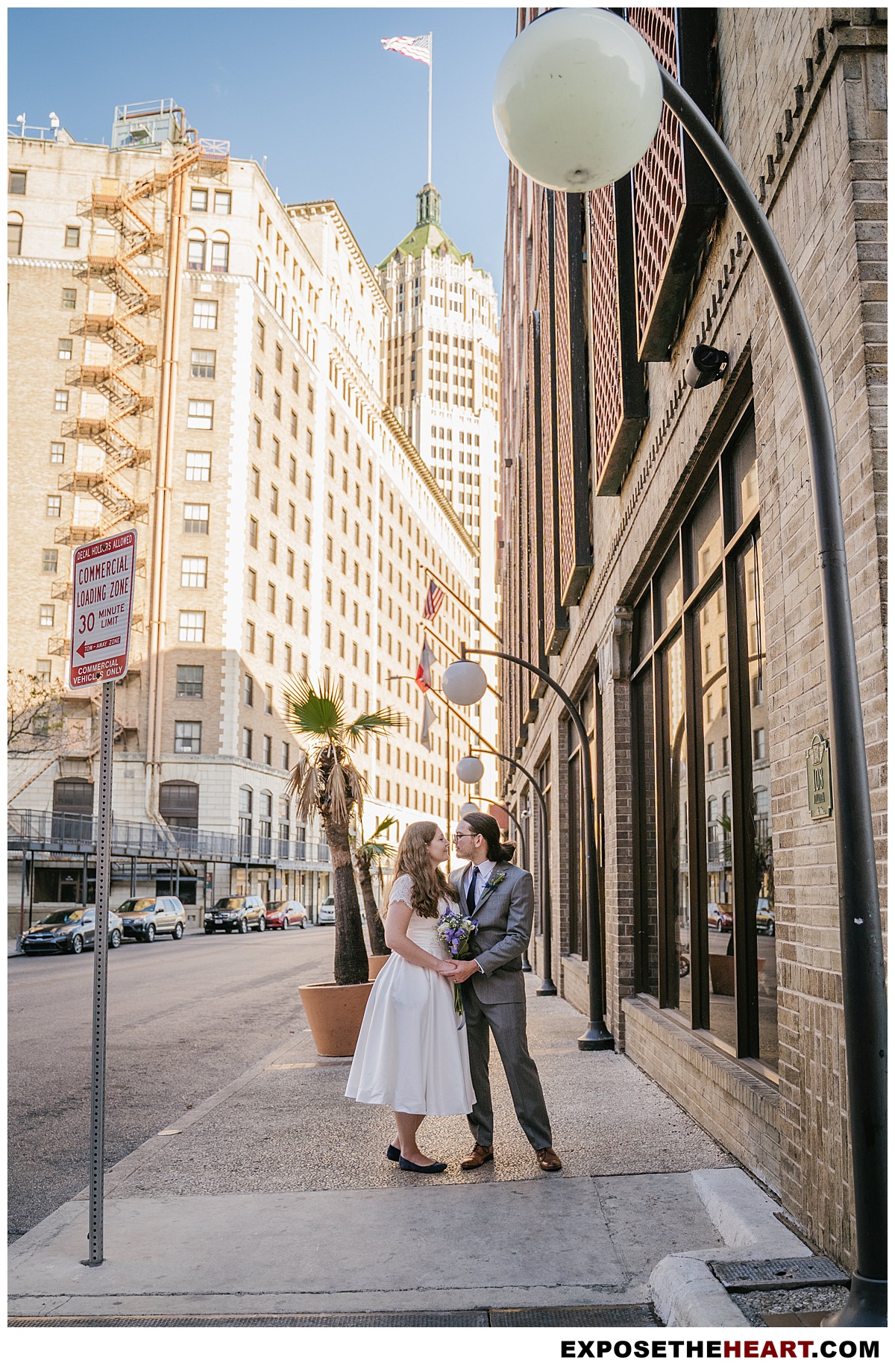 Bride and Groom posing in downtown San Antonio with tower of life building behind them