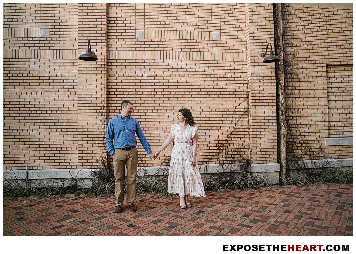Engagement pictures San Antonio couple in front of textured brick wall at Pearl Brewery.