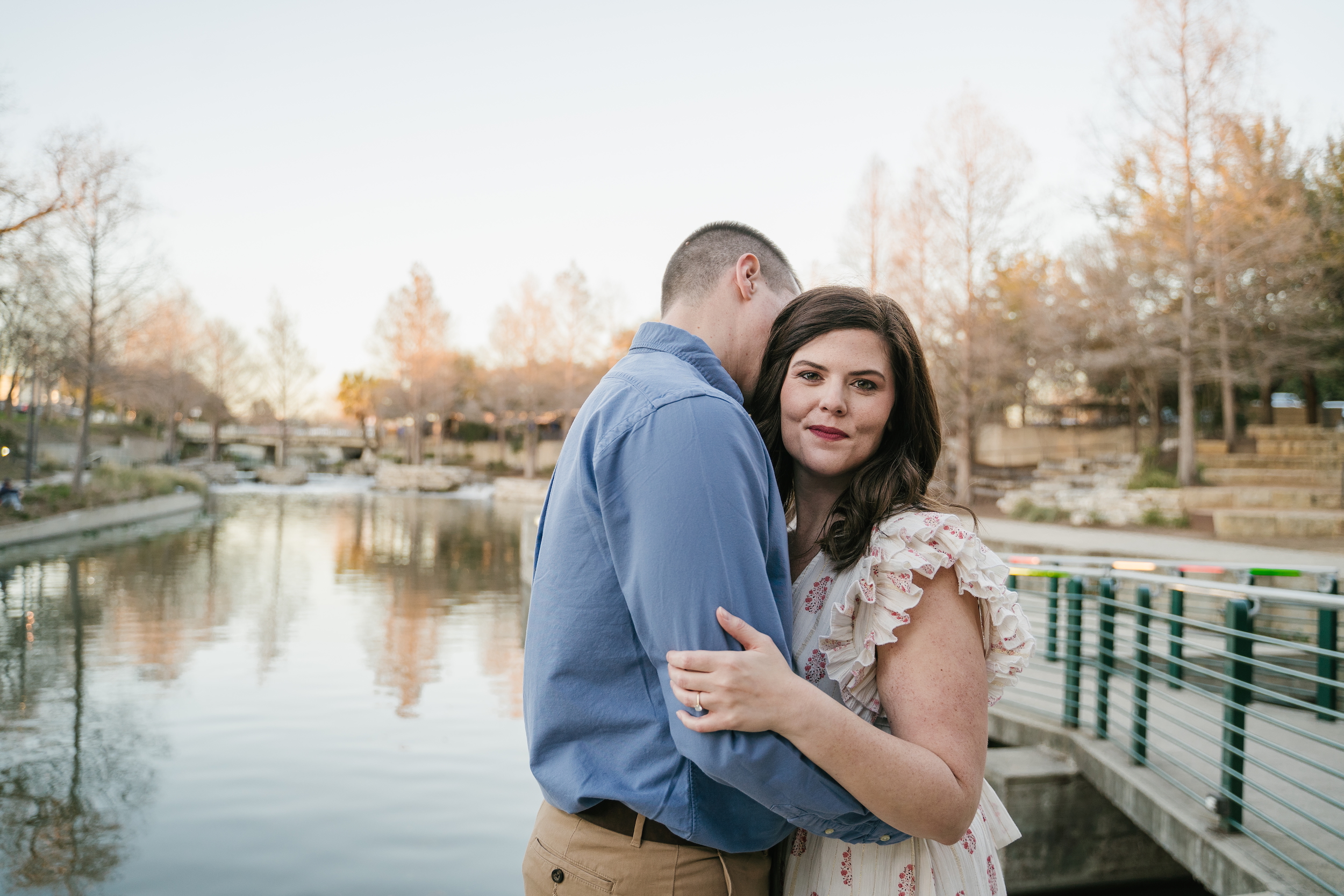 Candid engagement photos in San Antonio at The Pearl with couple walking dogs at sunset on Riverwalk